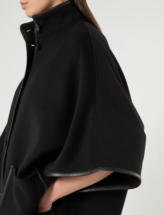 Black cape with stand collar, faux leather trim, snap-button front, and side pockets.