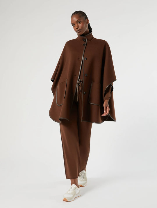 Biscuit cape worn over slim pants, stand collar with buttons, faux leather trim