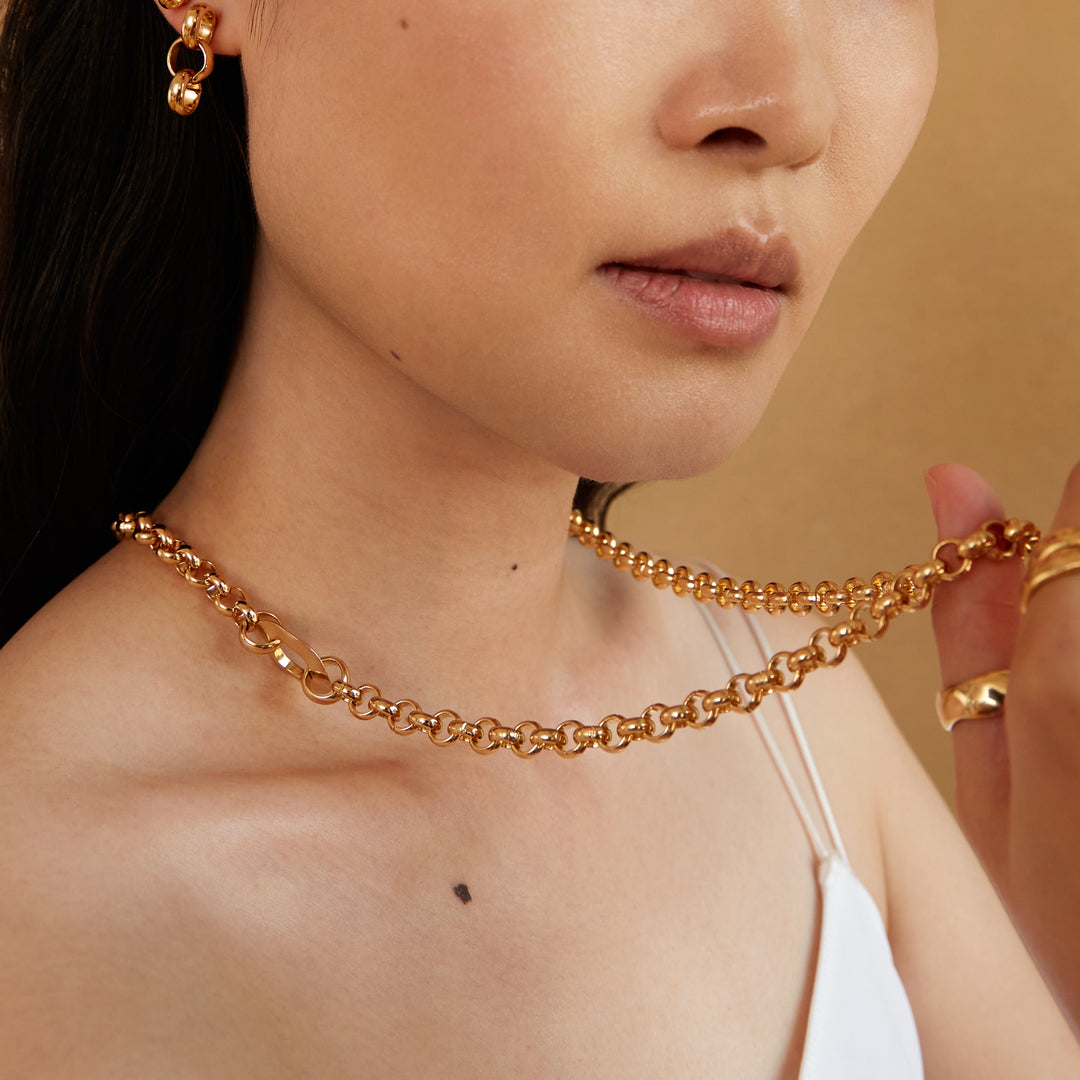 Layered chain necklace worn by model, showing convertible styling with multiple gold chains