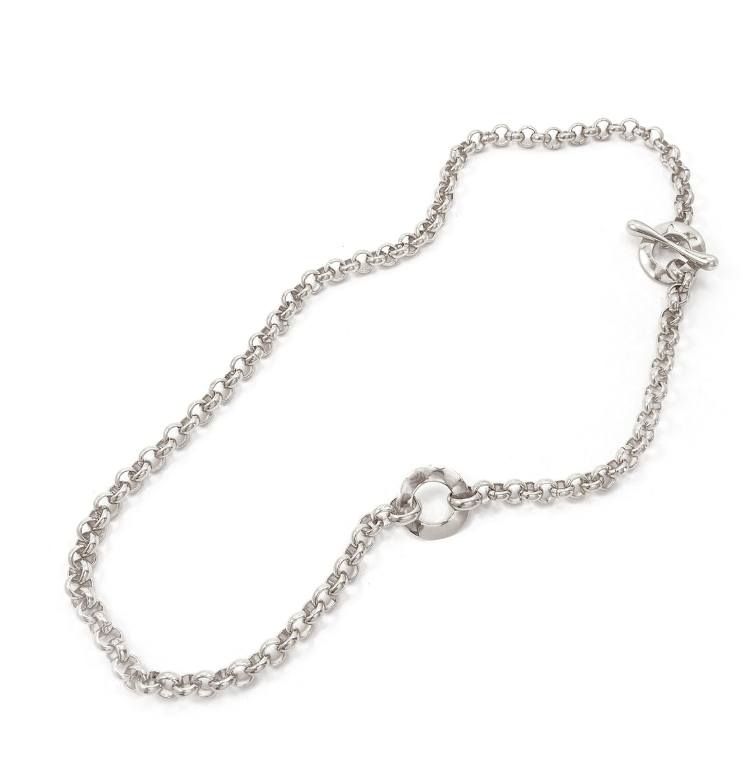 Silver chain necklace with toggle clasp and circular accent link laid flat