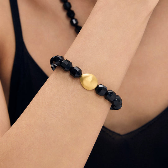 Black faceted bead bracelet with round gold charm at center