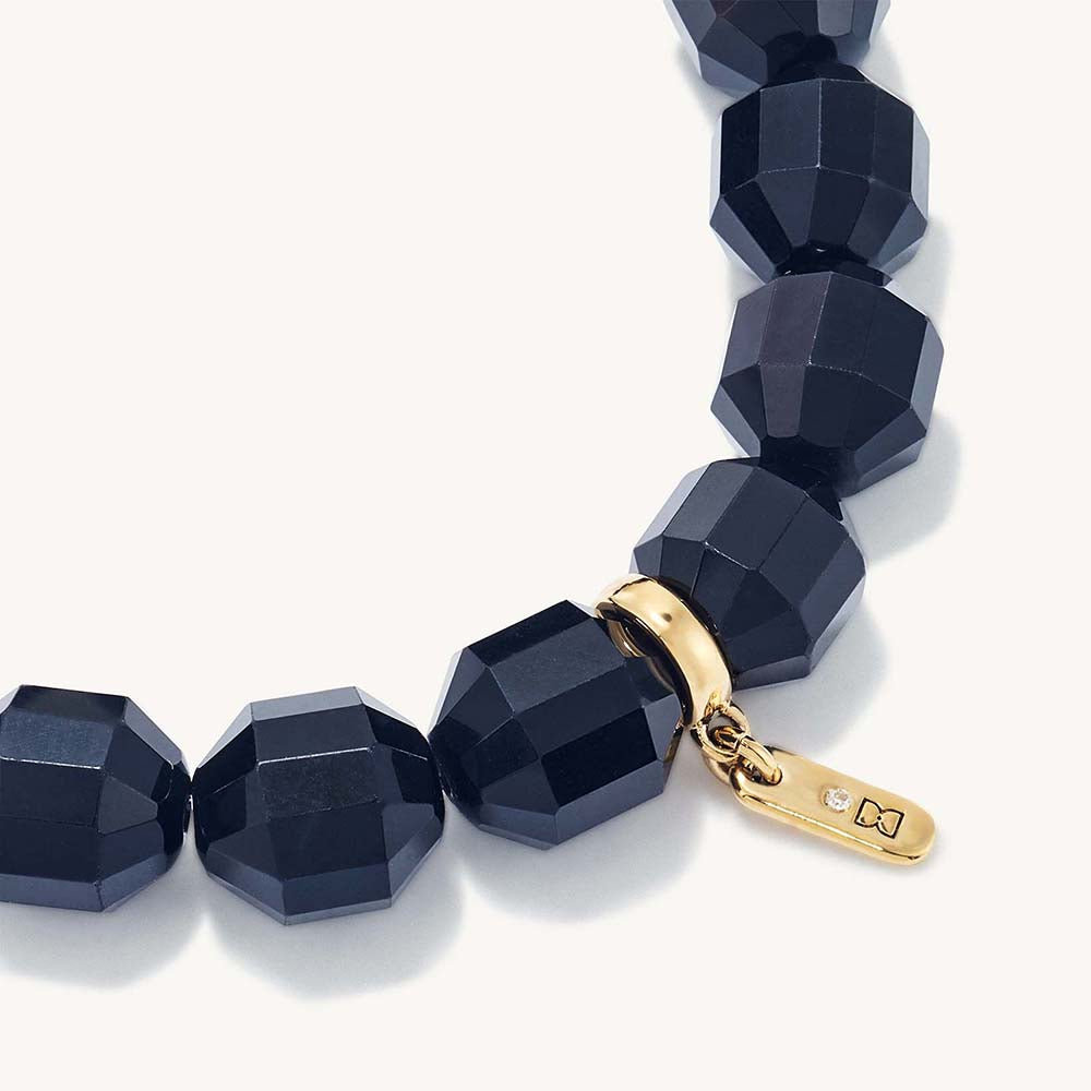 Close-up of black cube beads bracelet with gold clasp tag and ring
