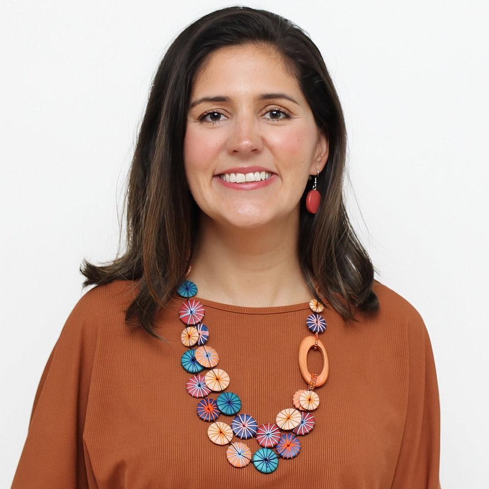 Statement necklace with colorful circular disc elements worn by model in rust colored top