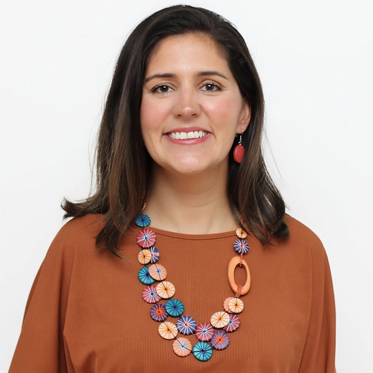 Statement necklace with colorful circular disc elements worn by model in rust colored top