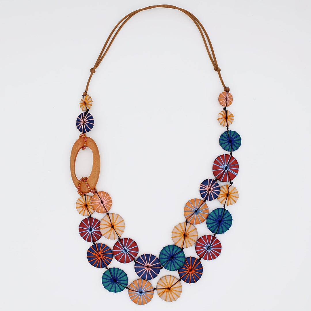 Statement necklace with colorful circular disc elements in warm autumn tones on leather cord