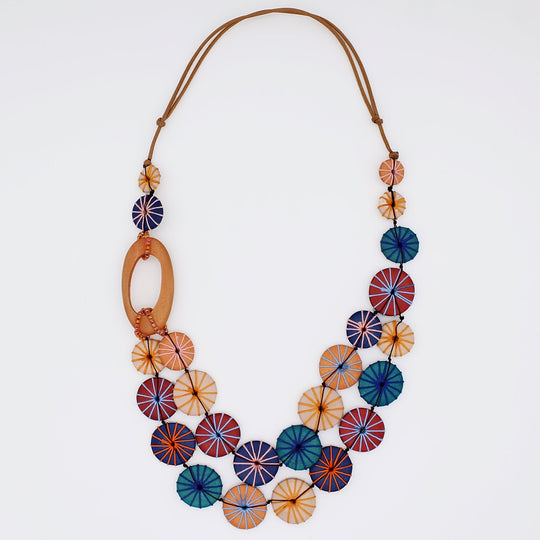 Statement necklace with colorful circular disc elements in warm autumn tones on leather cord
