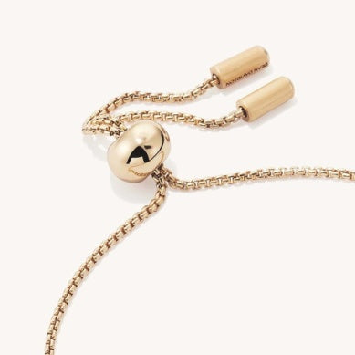 Gold-tone chain bracelet with round center charm and black detail