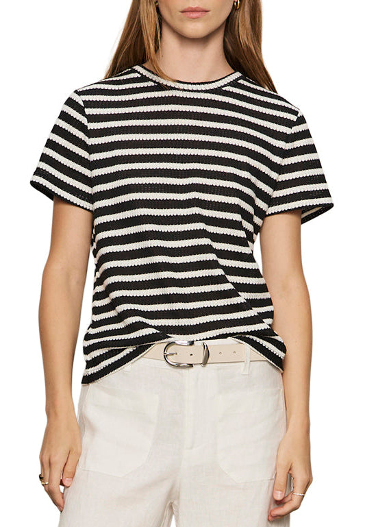 Person wearing a black and white striped shirt with white pants on a white background