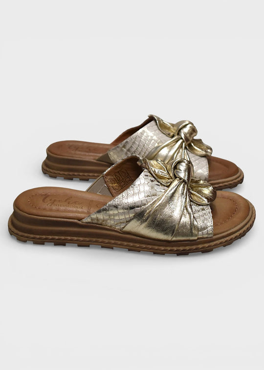 Gold sandals with a bow on a light gray background