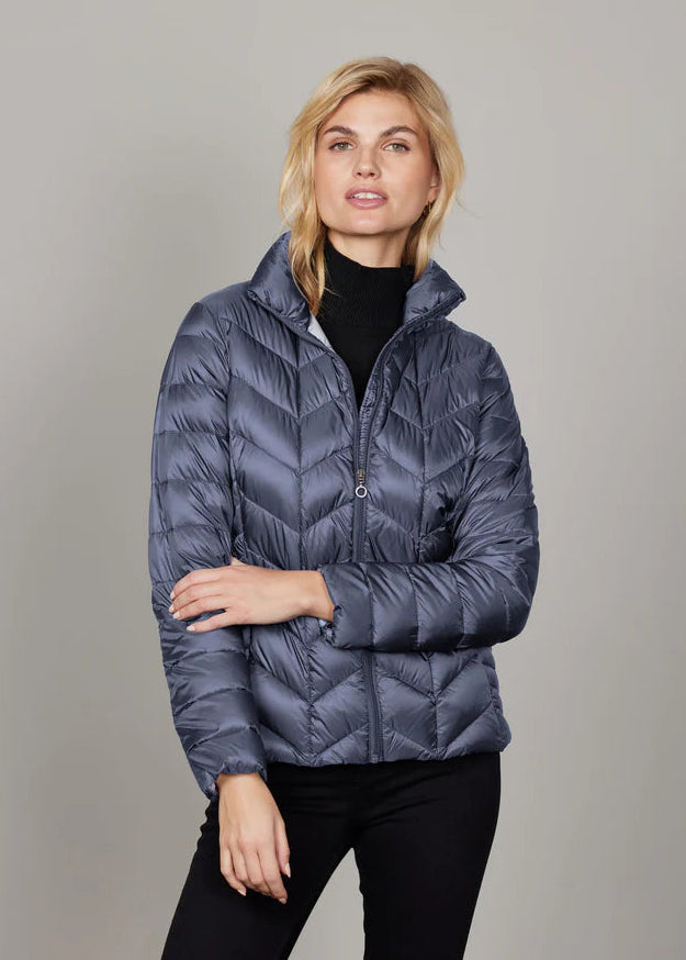 Woman wearing a blue quilted jacket against a gray background