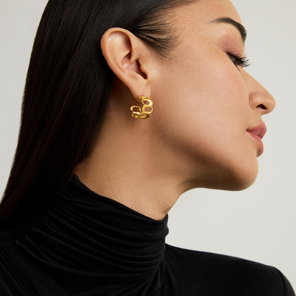 Gold chain-link huggie hoop earring worn by model, profile view showing sculptural linked design