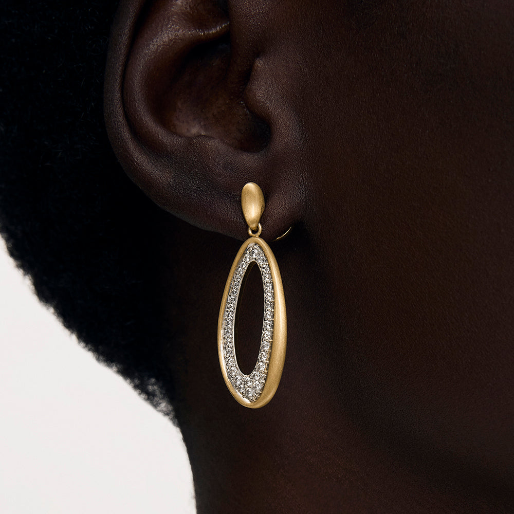 Oval drop earring with matte gold frame and pavé crystal interior, shown on model's ear