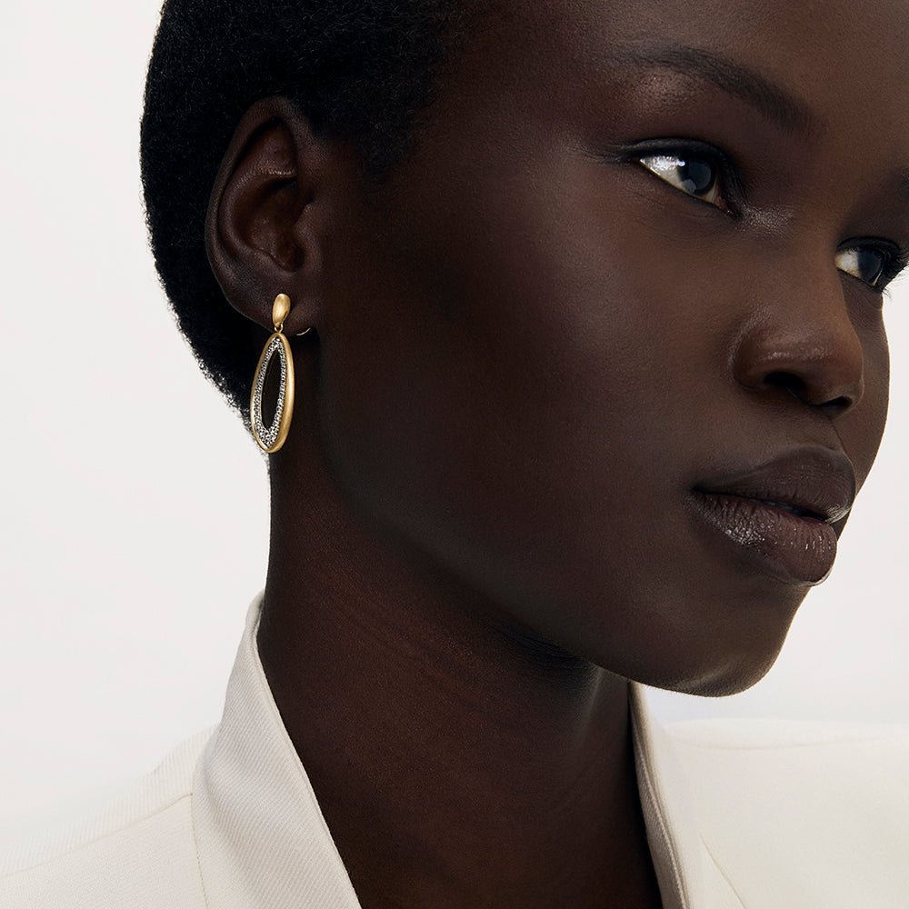 Oval drop earring with gold frame and crystal pavé detail, worn on model's ear