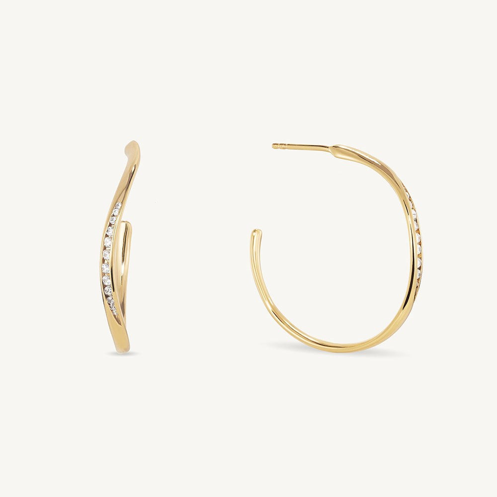 Gold hoop earrings with twisted design and pavé white crystal accents, pair shown