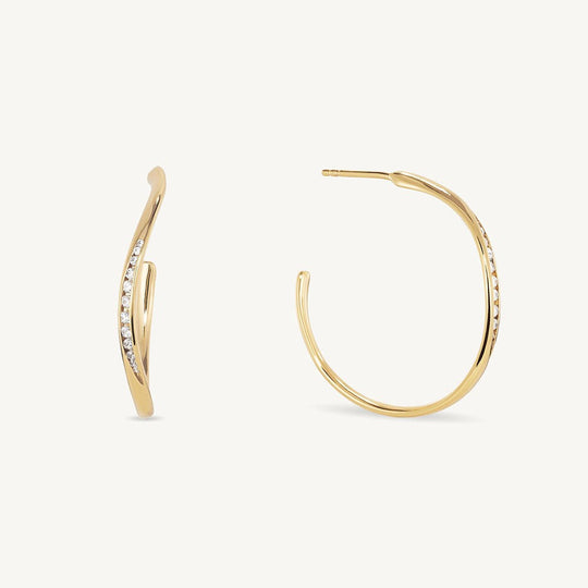Gold hoop earrings with twisted design and pavé white crystal accents, pair shown