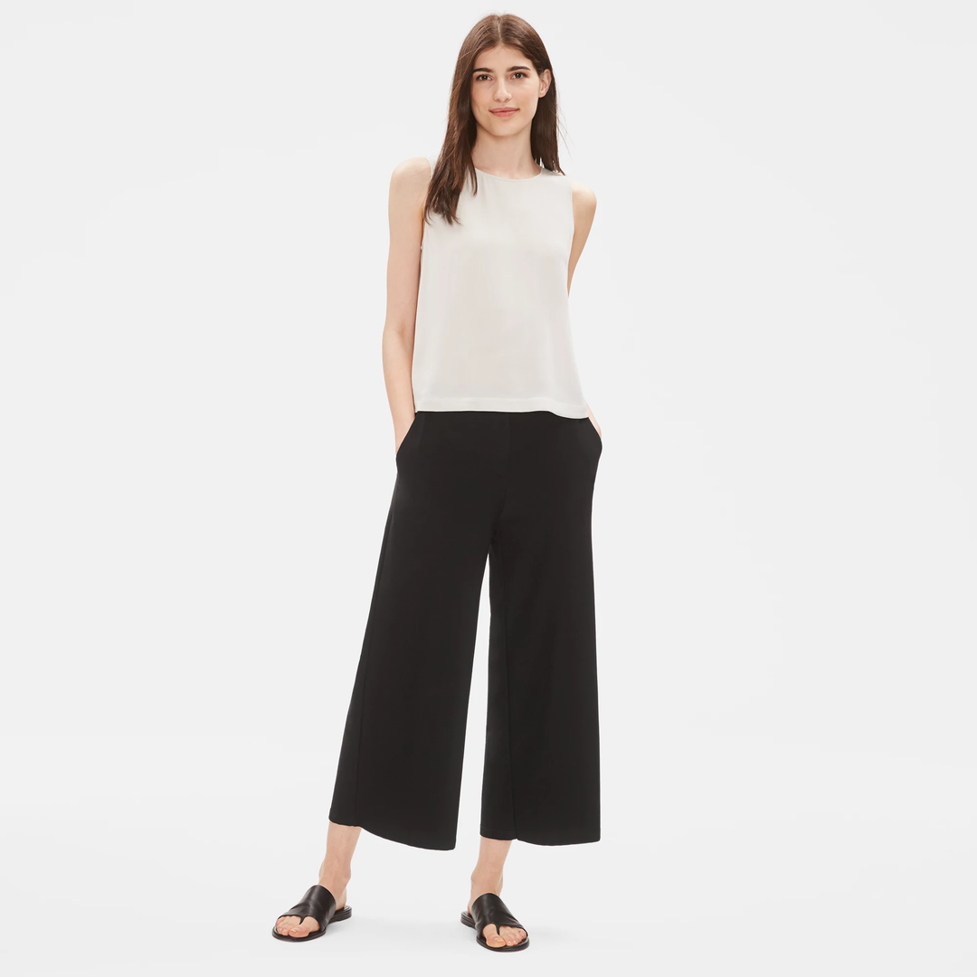 Black wide-leg cropped pants worn by model with white sleeveless top and black sandals