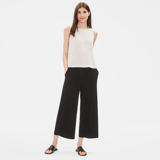 Black wide-leg cropped pants worn by model with white sleeveless top and black sandals