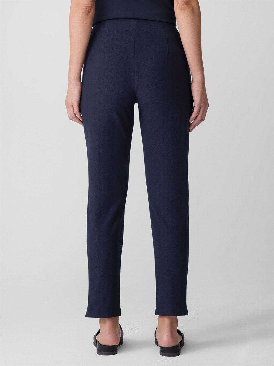 Dark blue slim leg pants shown from behind on model against neutral background