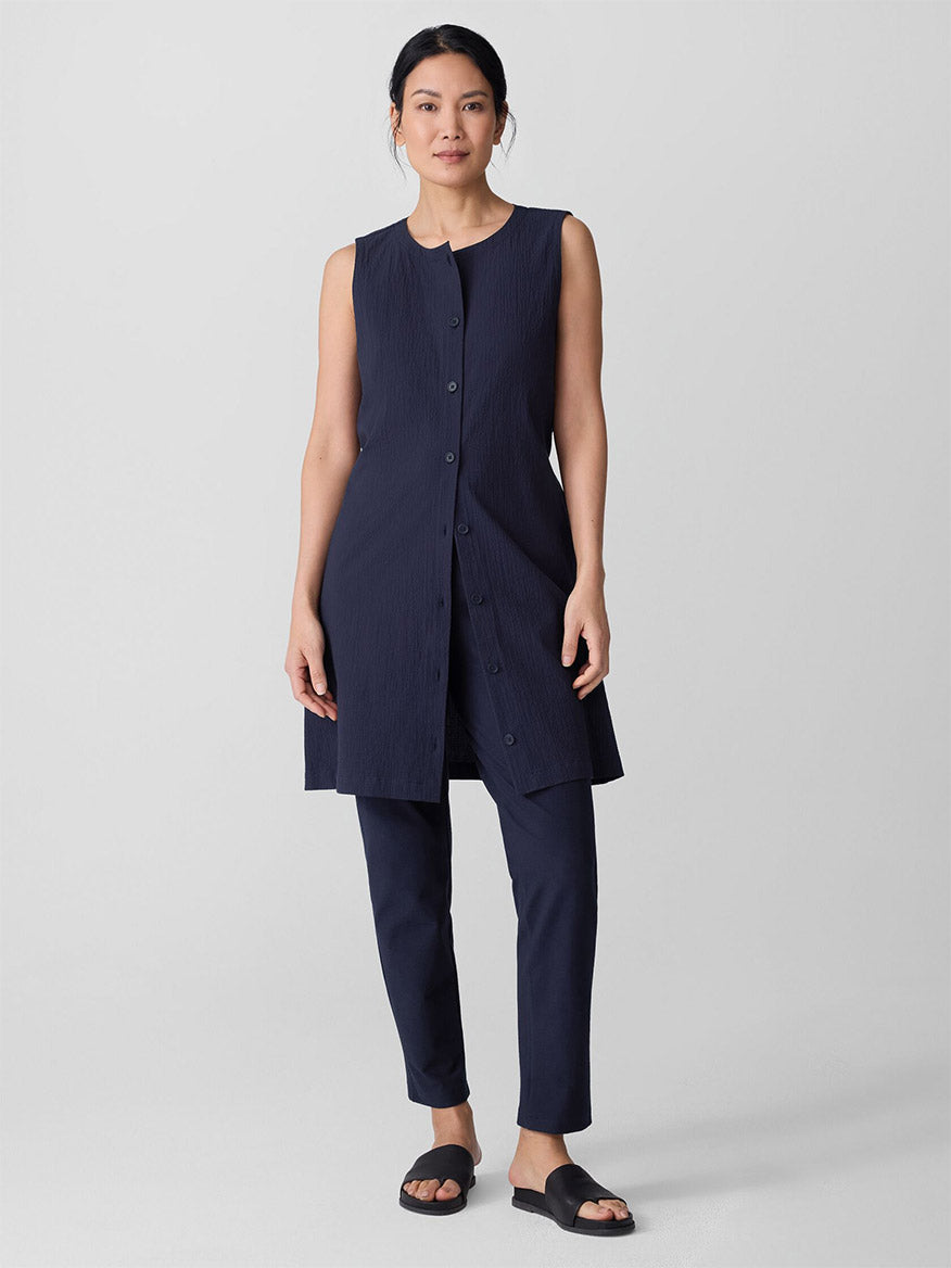 Woman wearing navy blue slim ankle pants with matching sleeveless tunic top, full body view