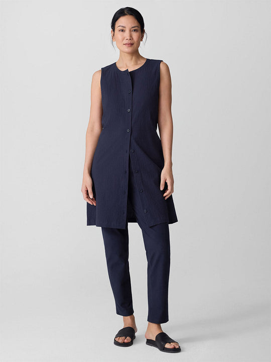 Woman wearing navy blue slim ankle pants with matching sleeveless tunic top, full body view