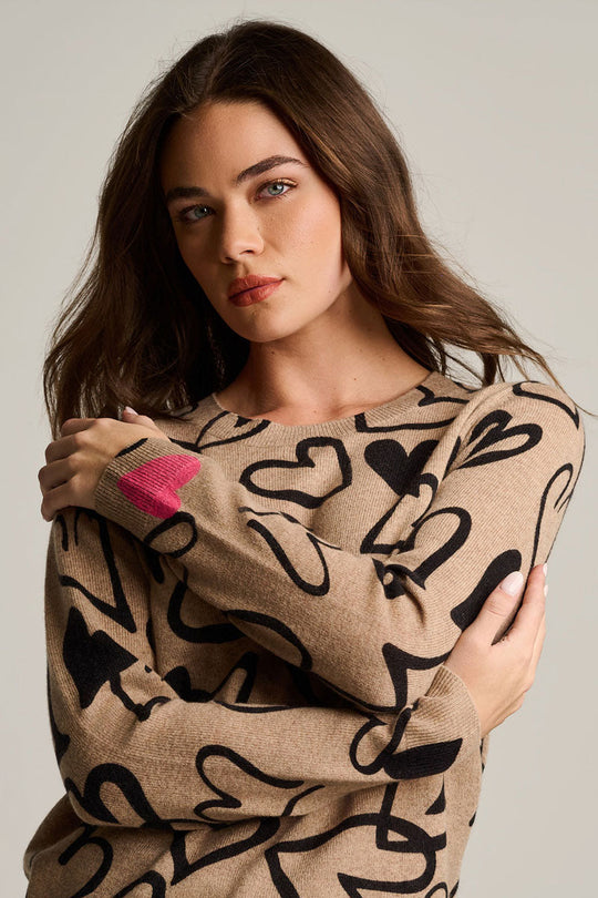 Cashmere heart-print sweater close-up, biscuit beige with black hearts and pink heart detail