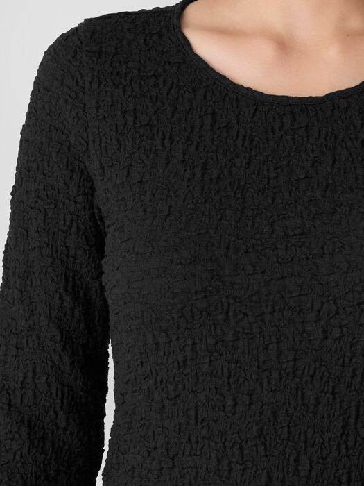 Close-up of textured bubble jacquard long-sleeve top with round neckline, worn by model
