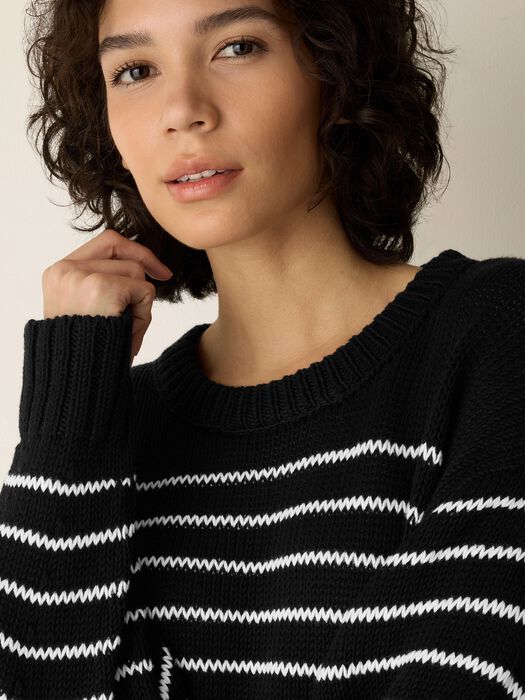 Black cotton sweater close-up with white striped knit across chest.