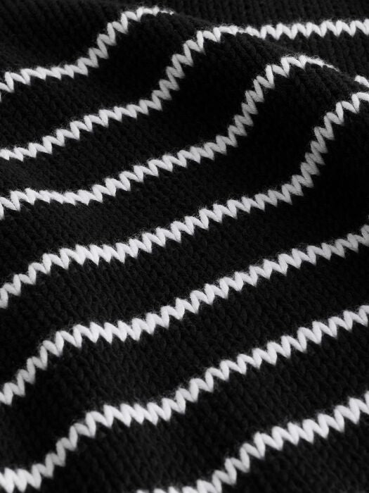 Close-up of black knit fabric with white wavy stripe pattern.