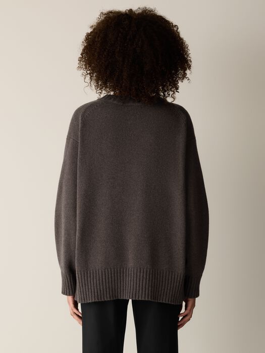 Oversized crew neck knit sweater in charcoal gray, back view on model, ribbed hem