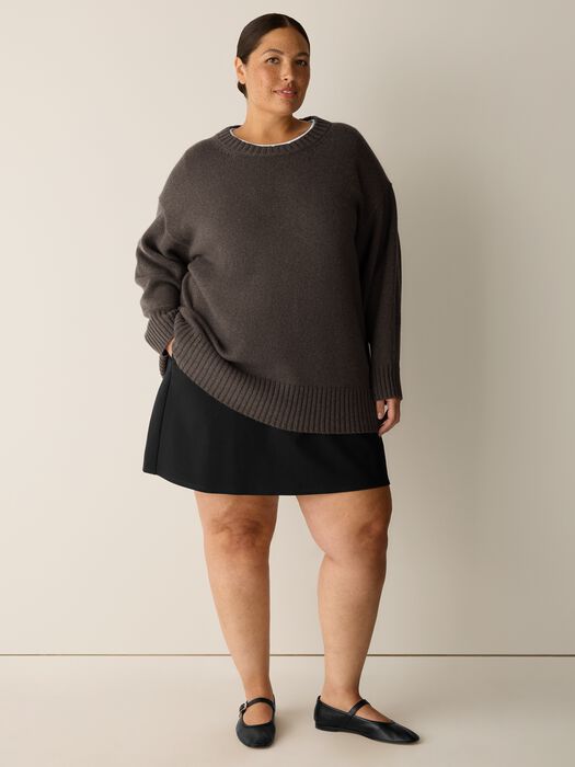 Oversized crew neck knit sweater in dark charcoal, worn with black mini skirt, front view on model