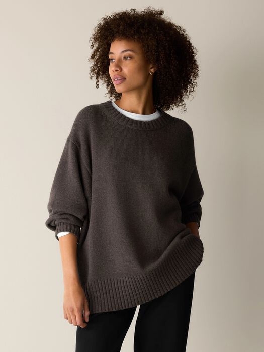 Oversized crew neck knit sweater in dark taupe, worn over white tee, three-quarter view on model