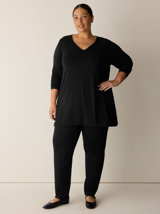Long-sleeve black V-neck A-line tunic top with flared hem, worn with matching pants, front view