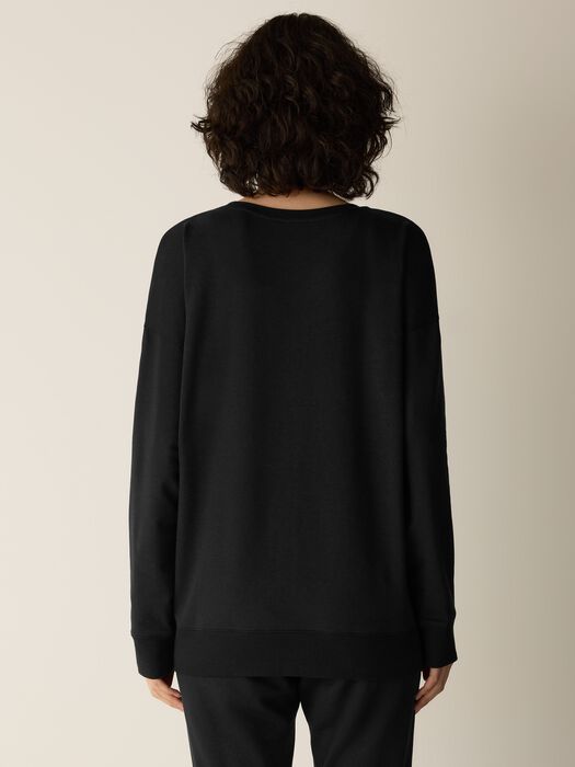 Black crew neck sweatshirt shown from the back on a model, long sleeves with ribbed cuffs
