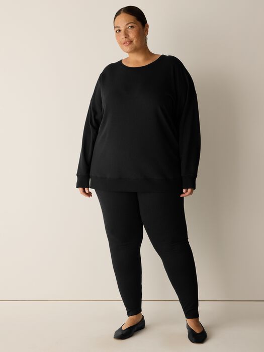 Long black crew neck sweatshirt with relaxed fit and ribbed cuffs, front view on model