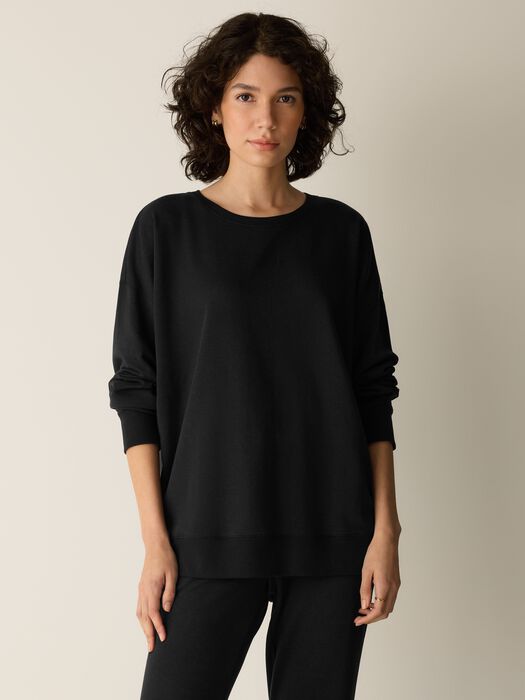 Long black crew neck sweatshirt with ribbed cuffs and relaxed fit, front view on model