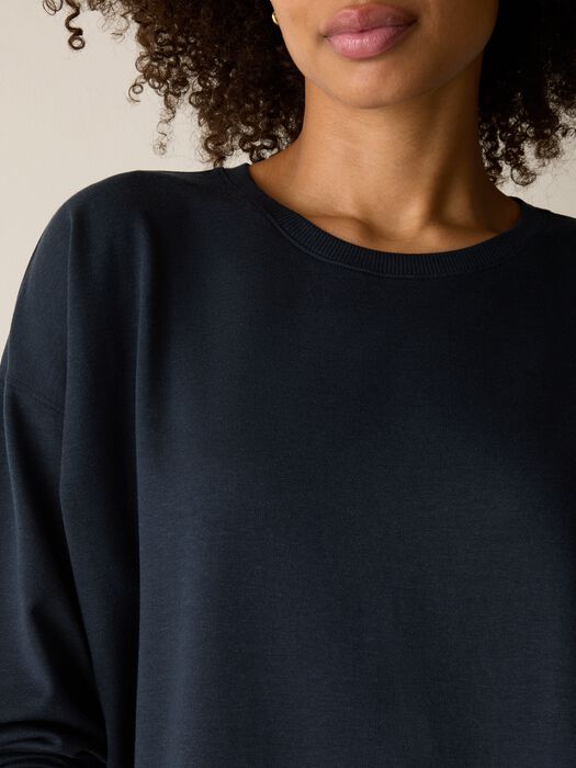 Dark navy crewneck sweatshirt with ribbed neckline, worn by model, close-up front view