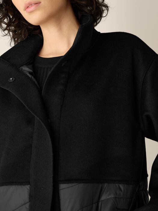 Black stand-collar coat neckline with button placket and gray quilted trim at hem.