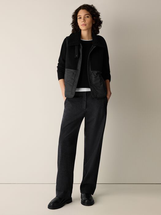 Black sleeveless vest with stand collar, front zip, and quilted paneling
