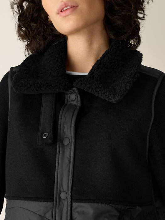 Black stand collar and snap placket on sleeveless vest with textured trim