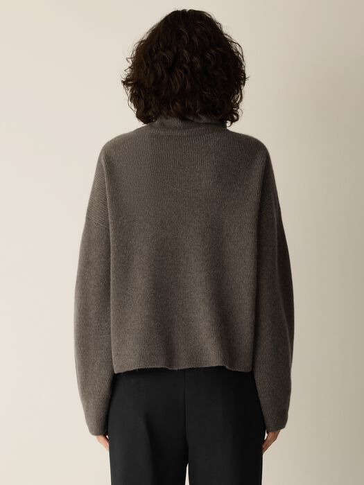 Back view of a ribbed cashmere turtleneck sweater with long sleeves and relaxed fit