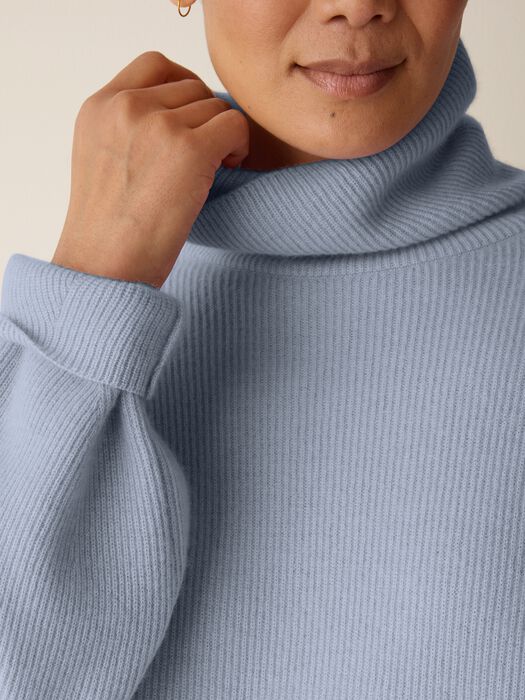 Light blue ribbed cashmere turtleneck sweater, close-up detail showing collar and sleeve