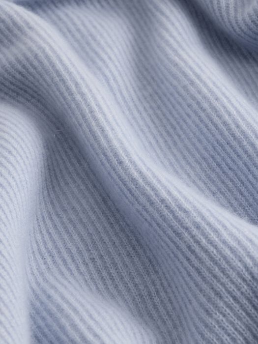 Close-up of ribbed cashmere knit fabric in soft light blue-grey tone showing texture detail