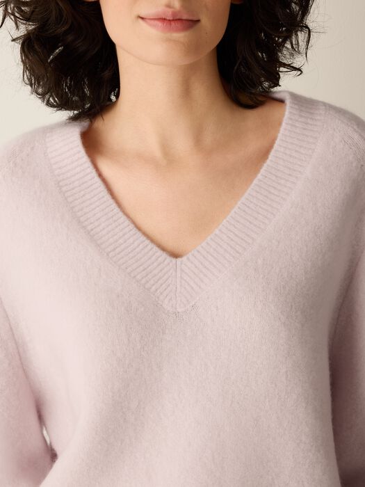 Light mauve V-neck sweater knit with ribbed collar and soft textured fabric.