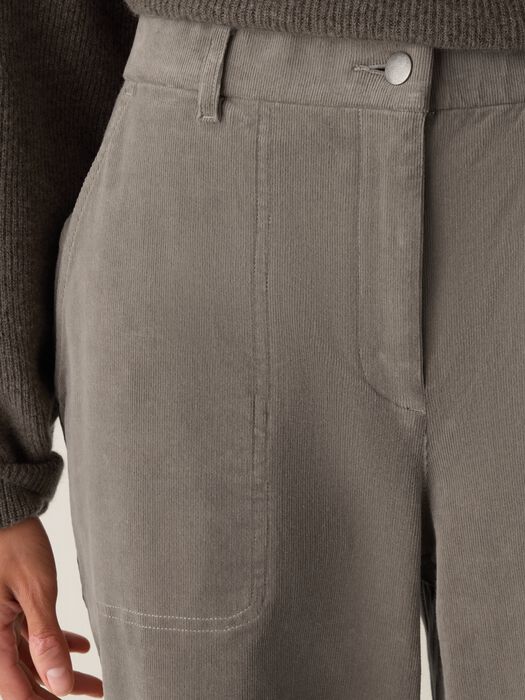Close-up of wide-leg corduroy pants with patch pockets and button closure, worn on model