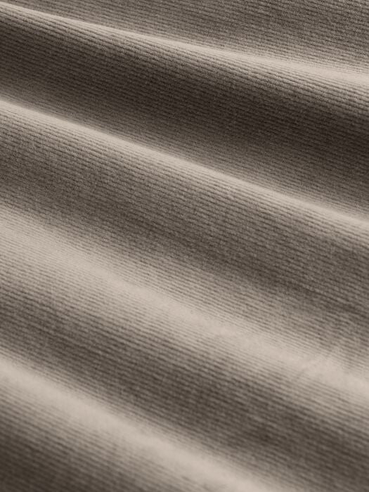 Close-up of fine-ribbed corduroy fabric in warm taupe, showing texture and soft drape