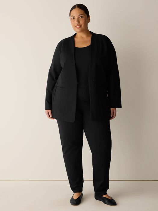 Black open-front blazer with collarless neckline and long sleeves, worn by model, front view