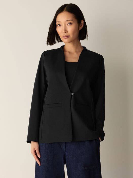 Black collarless blazer with single button closure and front pockets, front view on model