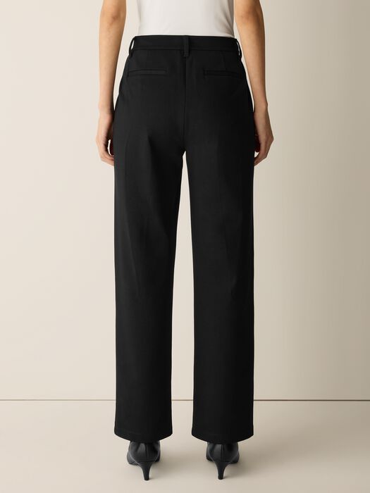 High-waisted wide-leg black trousers shown from behind on model wearing kitten heels