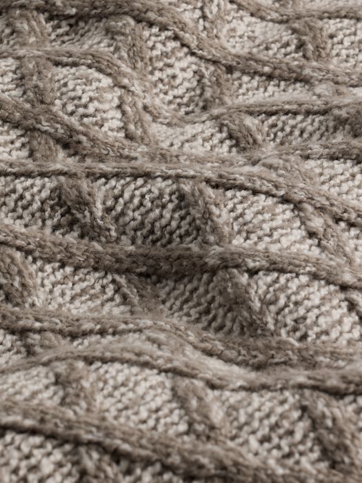 Close-up of textured cable-knit boucle fabric in warm beige showing argyle-like pattern detail