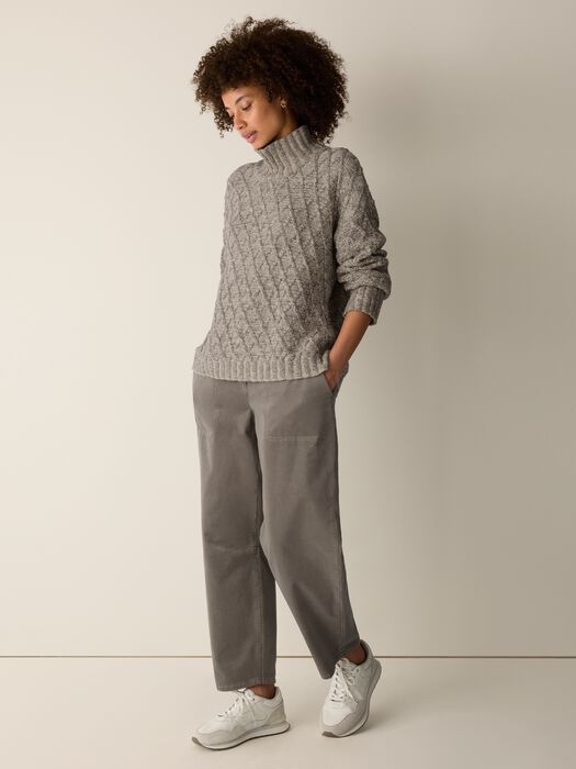 Cable-knit turtleneck sweater with argyle pattern in gray, worn by model with gray trousers
